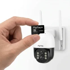 Ръка показва 128GB MicroSD карта пред бяла безжична камера FipTec, монтирана на стена, подчертавайки възможността за сигурно локално съхранение на записите за пълна защита и вашето спокойствие.