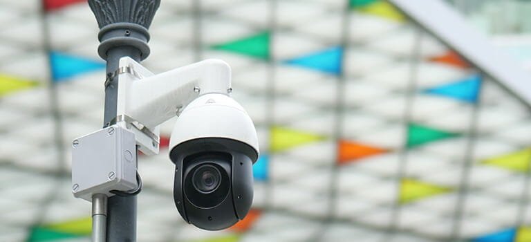 ip камера за външен монтаж заснета на преден фон а отзад шарен покрив