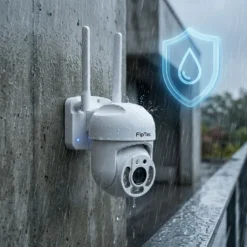 Бяла външна WiFi камера FipTec LO11, монтирана на бетонна стена под дъжда, показваща своята водоустойчивост чрез защитен щит. Тази надеждна охрана осигурява вашата сигурност и пълно спокойствие във всяко време.