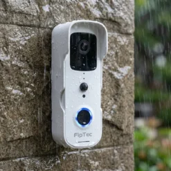 Бял смарт видео звънец FipTec с висока водоустойчивост, монтиран на външна стена по време на дъжд. Този продукт осигурява надеждна охрана на входа и пълно спокойствие при всякакви метеорологични условия чрез интелигентен контрол.
