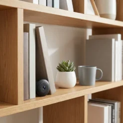 Дискретна мини WiFi камера FipTec LM07-Pro, поставена на дървена етажерка до книги и цвете, осигуряваща невидима защита и спокойствие за дома чрез лесен смарт контрол.