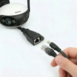 Ръка, свързваща водоустойчив PoE LAN адаптер FipTec към кабела на охранителна камера за надеждна мрежова връзка и сигурност. Насладете се на лесен контрол и дълготрайно спокойствие за вашето семейство.