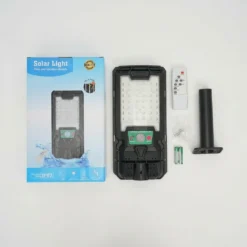 Пълен комплект соларна LED лампа FipTec с включени дистанционно управление, батерии, монтажна стойка и кутия на бял фон. Осигурете си надеждна защита и дискретна сигурност с лесен контрол.