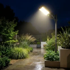 Мощна безжична соларна LED лампа FipTec, монтирана на стълб, осветява градинска пътека през нощта. Осигурява надеждна външна охрана за пълно спокойствие и дискретна сигурност на вашия имот.